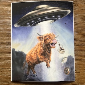 May include: A whimsical illustration depicts a brown Highland cow being beamed up by a UFO. Coffee and a donut are also being lifted. The background features a night sky and a landscape. The image is on a white background.