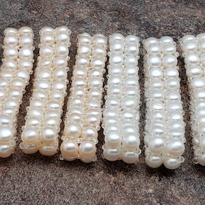 May include: Six strands of white pearl beads, each strand is approximately 10 inches long and composed of small, round pearls.