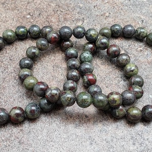 K&ouml;nnte beinhalten: Drei gr&uuml;ne, rote und schwarze Edelstein-Armb&auml;nder mit runden Perlen.