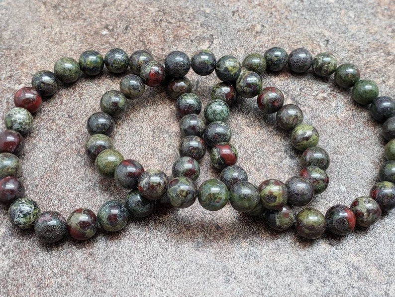K&ouml;nnte beinhalten: Drei gr&uuml;ne, rote und schwarze Edelstein-Armb&auml;nder mit runden Perlen.