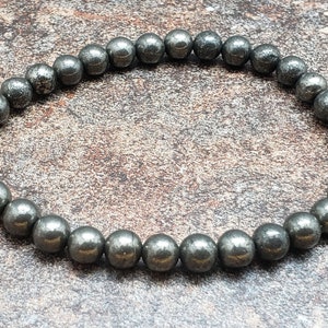 May include: A bracelet made of small, round, dark gray pyrite beads.
