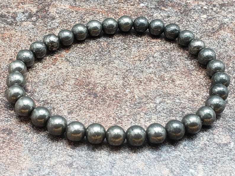 May include: A bracelet made of small, round, dark gray pyrite beads.