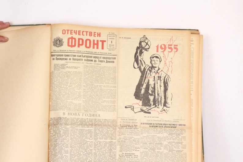 May include: A vintage newspaper from 1955 titled "Otechestven Front" with a black and white illustration of a person holding a grenade. The text "В НОВА ГОДИНА" is printed at the bottom of the page.