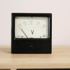 Stary edukacyjny woltomierz, elektryczne urządzenie pomiarowe, gadżet elektryczny, analogowy, obudowa z bakelitu