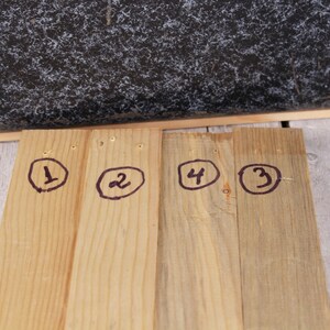 May include: Four wooden planks with numbers 1, 2, 3, and 4 circled in black marker.