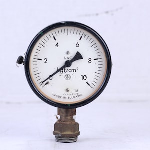 Può includere: Un manometro rotondo bianco e nero con un ago nero. Il manometro legge in kgf/cm2 ed è etichettato "MADE IN BULGARIA".