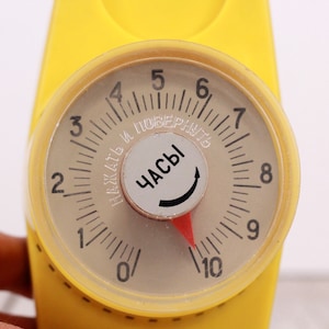 May include: A yellow timer with a round dial that reads "Часы" (meaning "hours" in Russian) and has numbers from 0 to 10. The timer has a red pointer and a black knob.