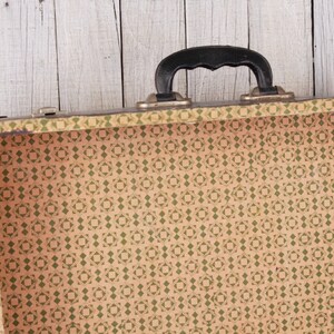 May include: An empty vintage suitcase with a black handle and a brown and green patterned lining.