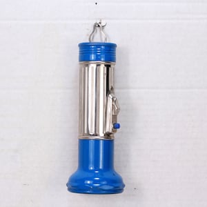 May include: A blue and silver flashlight with a ribbed body and a side switch. The flashlight has a blue plastic cap and a blue plastic base.