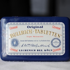 May include: A rectangular, dark blue box with a white label featuring gold lettering that reads "Original BULLRICH-TABLETTEN." The label includes text in German and a Swiss cross emblem. The box contains 156 tablets.