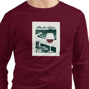 May include: A maroon long-sleeve t-shirt with a graphic print of a glass of red wine and the text "Côtes du Rhône".