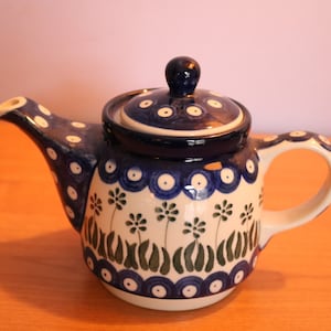 May include: A blue and white ceramic teapot with a floral design. The teapot has a lid and a handle.