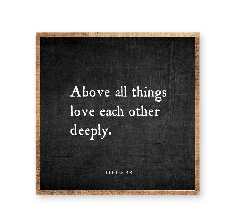 May include: A square wooden sign with a dark charcoal black background and a natural light brown wood frame. The text in white reads: Above all things love each other deeply. 1 PETER 4:8. The surface has a visible wood grain texture.