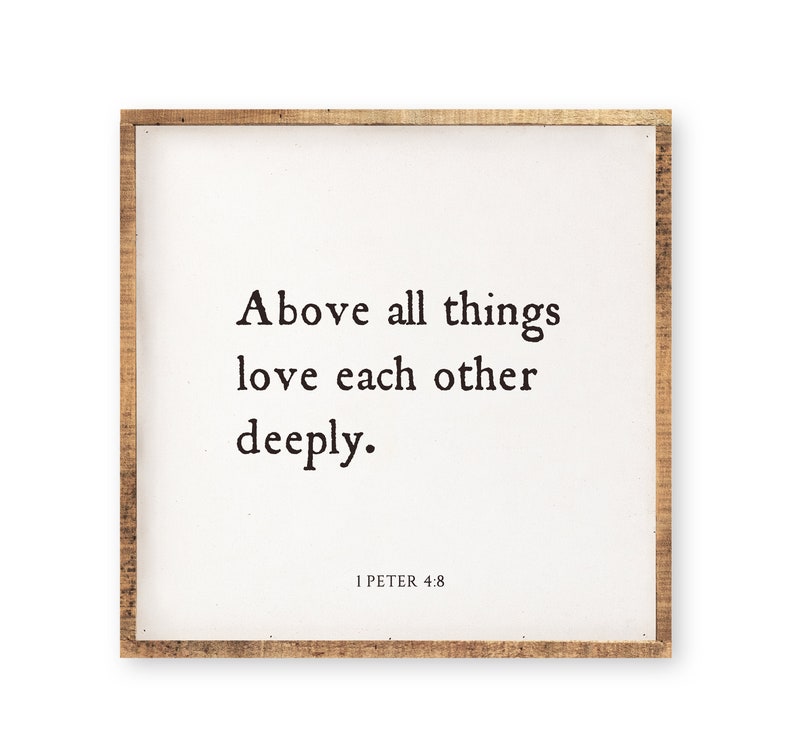 May include: A square wooden wall sign with a natural light brown wood frame and a white center panel. The text in black serif font reads: Above all things love each other deeply. 1 PETER 4:8 is printed in smaller black text at the bottom.