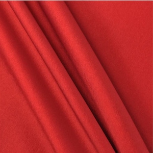 May include: Close-up of a smooth, red fabric with a soft, silky texture. The fabric is folded in a way that creates a series of gentle curves and folds.