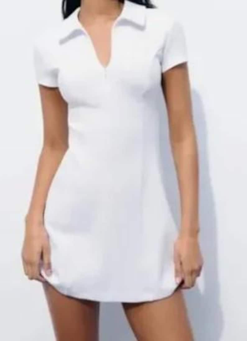 May include: A white collared dress with a zipper closure and short sleeves.