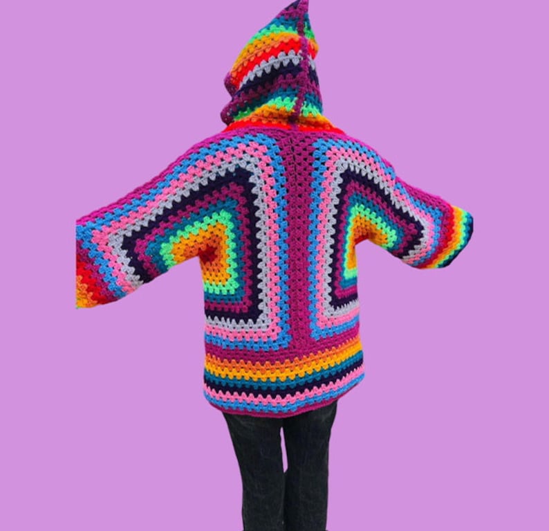 Peut inclure: Un cardigan &agrave; capuche en crochet color&eacute; avec un motif arc-en-ciel. Le cardigan est fait de plusieurs couleurs, dont le rose, le violet, le bleu, le vert, le jaune, l'orange et le rouge.