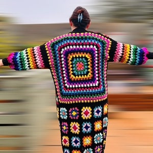 May include: A long, black crochet cardigan with a colorful geometric pattern. The cardigan has long sleeves and a loose fit.