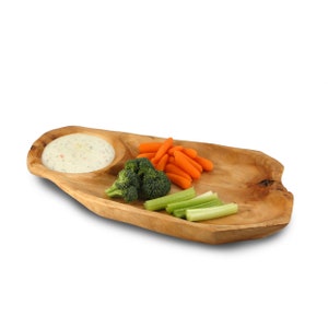 May include: A wooden serving tray with a dip bowl and two sections for snacks. The tray is filled with carrots, broccoli, and celery.