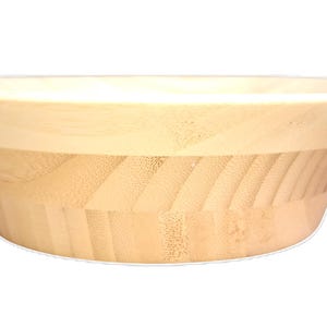 Puede incluir: Un cuenco de madera de color claro con un dise&ntilde;o amplio y acampanado. El cuenco tiene un borde liso de color claro y una secci&oacute;n inferior texturizada de color claro. El cuenco se utiliza probablemente para servir alimentos o como objeto decorativo.