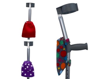 Puede incluir: Dos muletas con fundas de tela de colores. Las fundas son de forro polar y tienen un patrón de lunares. Una funda es roja, otra es morada con lunares blancos y otra es gris con lunares multicolores.