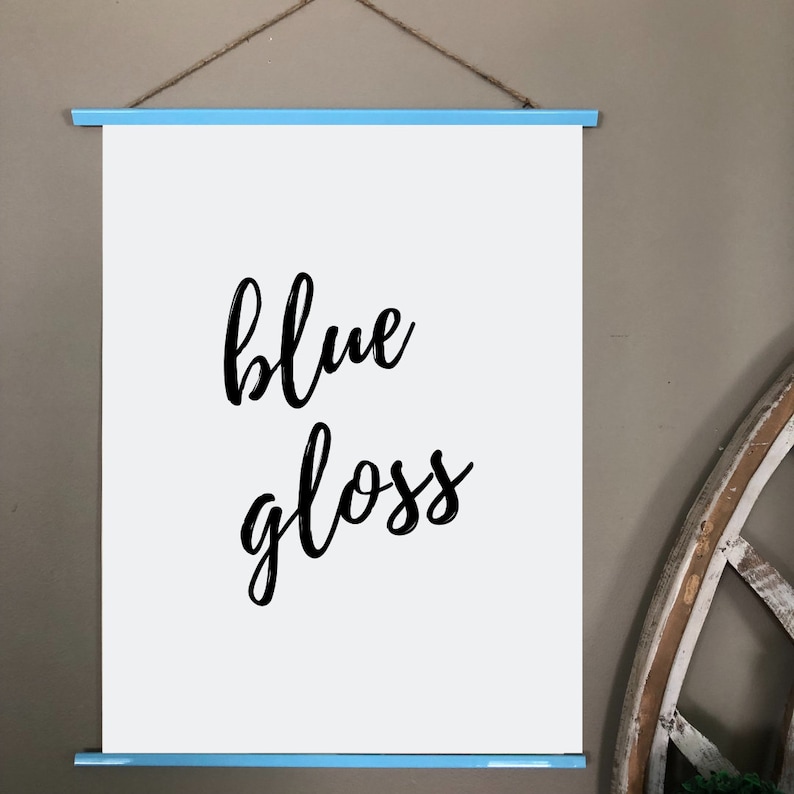 Pu&ograve; includere: Una tela bianca con una cornice blu, appesa a un muro. La tela ha le parole "blue gloss" scritte in corsivo nero.