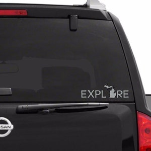 May include: A black car with a gray decal on the back window. The decal says "EXPLORE" with an outline of the state of Michigan.