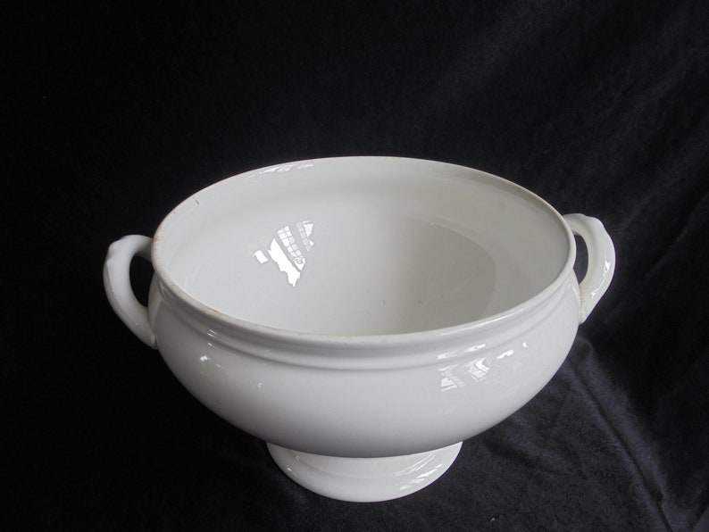 May include: White porcelain serving bowl with two handles and a pedestal base.
