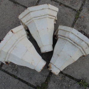 Op de afbeelding: Drie witte keramische of gipsen bloempotonderdelen met een decoratief, geribbeld ontwerp. De onderdelen zijn kegelvormig met een brede opening aan de bovenkant en een smalle opening aan de onderkant.