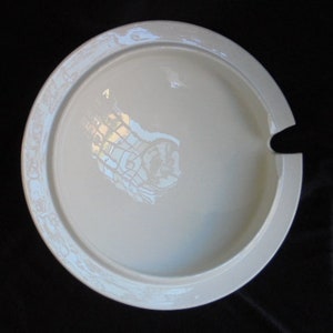 May include: White ceramic serving dish with a decorative design around the edge. The dish has a small spout on the side.
