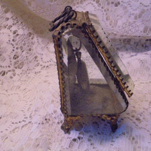 May include: A gold-toned glass display case with a beveled glass front and ornate metal trim. The case is open and empty.