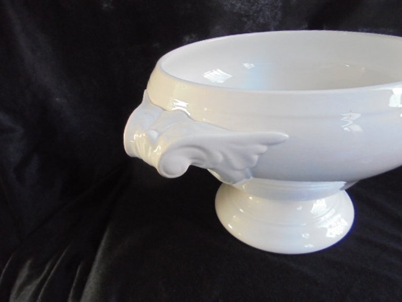 May include: White ceramic serving bowl with two ornate handles and a pedestal base.