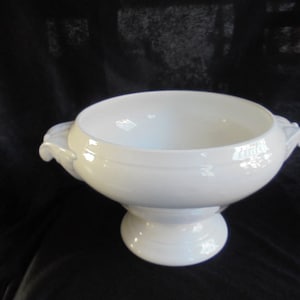May include: A white porcelain serving bowl with two handles and a pedestal base.