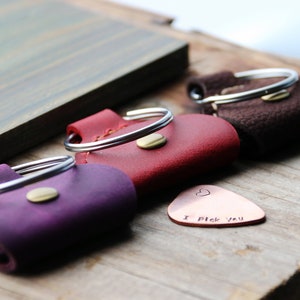 Könnte beinhalten: Drei Leder-Picks mit Metallringen und ein Kupfer-Plektrum mit dem Text "I pick you".