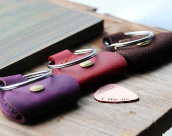 May include: Three leather guitar picks with metal rings and a copper guitar pick with the text "I pick you".