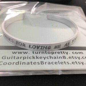 May include: Silver bracelet with the inscription "Thanks for loving me as you do". The bracelet is on a white background with the website address "www.turntopretty.com" and two other website addresses.