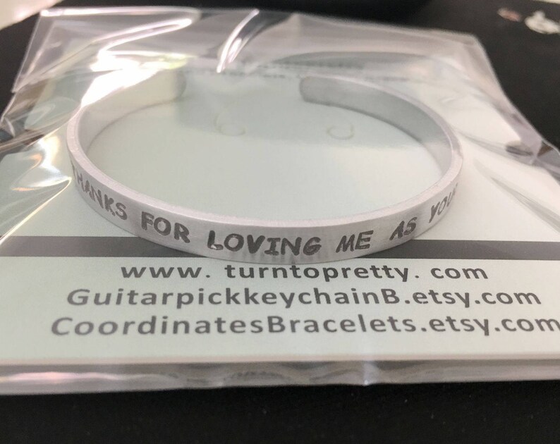 May include: Silver bracelet with the inscription "Thanks for loving me as you do". The bracelet is on a white background with the website address "www.turntopretty.com" and two other website addresses.