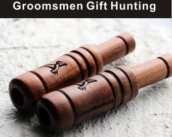 May include: Two wooden duck calls with a dark finish. Each call features a carved bird graphic and the word "Groomsmen". The calls are designed for hunting and are likely intended as gifts.