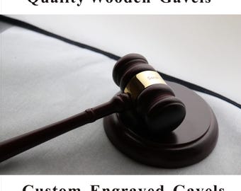 May include: A dark brown wooden gavel with a matching base. The gavel has a gold band with the name "Sarah" engraved on it. The image also includes the text "Quality Wooden Gavels" and "Custom Engraved Gavels".