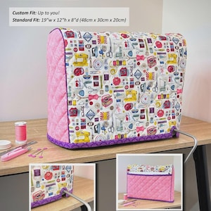 May include: A sewing machine cover featuring a white fabric with a colorful sewing-themed print, pink quilted side panels, and purple trim. The cover has a standard fit of 19 inches wide by 12 inches high by 8 inches deep. Text includes Andrie Designs.