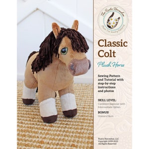 May include: A plush toy horse with a tan body, brown mane, and white leg markings. The horse has large, expressive eyes and is standing on a woven rug. The image includes text that reads "Classic Colt Plush Horse".
