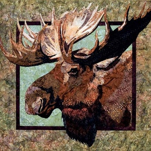 May include: A detailed textile art piece featuring a moose head with large antlers. The moose is rendered in shades of brown, tan, and black, set against a light green background within a dark frame. The border has a swirling pattern.