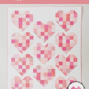 May include: A quilt pattern titled Scrappy Hearts No. 132 by Quilty Love featuring a white background with ten heart-shaped blocks made of various pink and red patterned fabric squares. The design includes baby, throw, and twin size options.