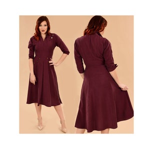 May include: A burgundy midi dress with a collared neckline, long sleeves, and a fitted waist. The dress has a flared skirt and features a button closure at the front.