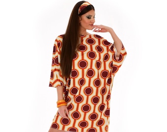 May include: A white, orange, and maroon geometric patterned dress with a scoop neck and three-quarter sleeves. The dress has a loose fit and is worn by a model with long brown hair and a headband.