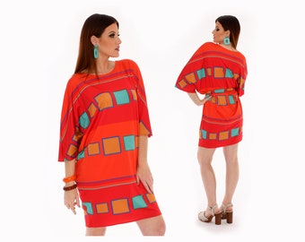 May include: A red, orange, and teal geometric print short-sleeved dress with a tie belt. The dress is loose-fitting and has a relaxed silhouette.