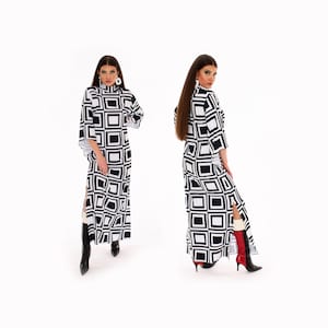 Puede incluir: Un vestido maxi de estampado geométrico en blanco y negro con cuello alto y mangas largas. El vestido tiene una abertura lateral y la modelo lleva botas negras.