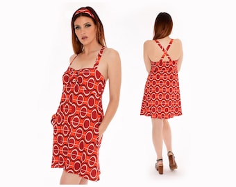May include: A red and white mini dress with a geometric pattern. The dress has a scoop neck, spaghetti straps, and a criss-cross back. The model is wearing a headband.