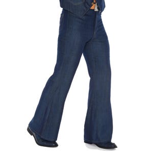 May include: Dark blue denim bell-bottom pants. The pants have a high waist and a wide flare from the knee down. The pants are paired with black dress shoes. The denim jacket is visible at the top of the image.