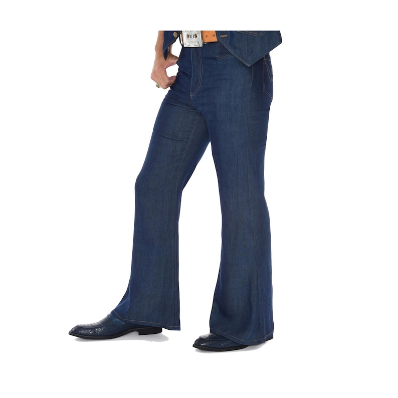 May include: Dark blue denim bell-bottom jeans. The jeans have a high waist and a flared leg from the knee down. The model is wearing a brown belt with a silver buckle and black shoes.